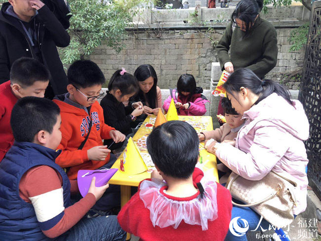 爸爸妈妈带着孩子参加亲子手工游戏。李雯 摄