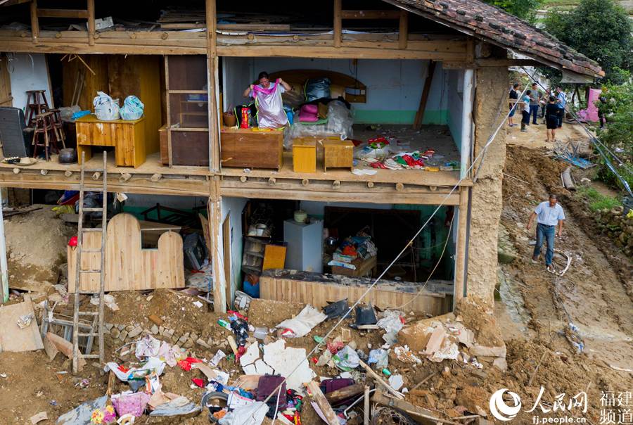 渭田鎮巨口村受災村民在安全的條件下，在自家受災的屋內整理日常用品並搬到安置點。