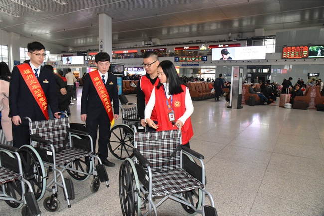 残联工作人员向火车站工作人员交接轮椅。吴晓烨摄