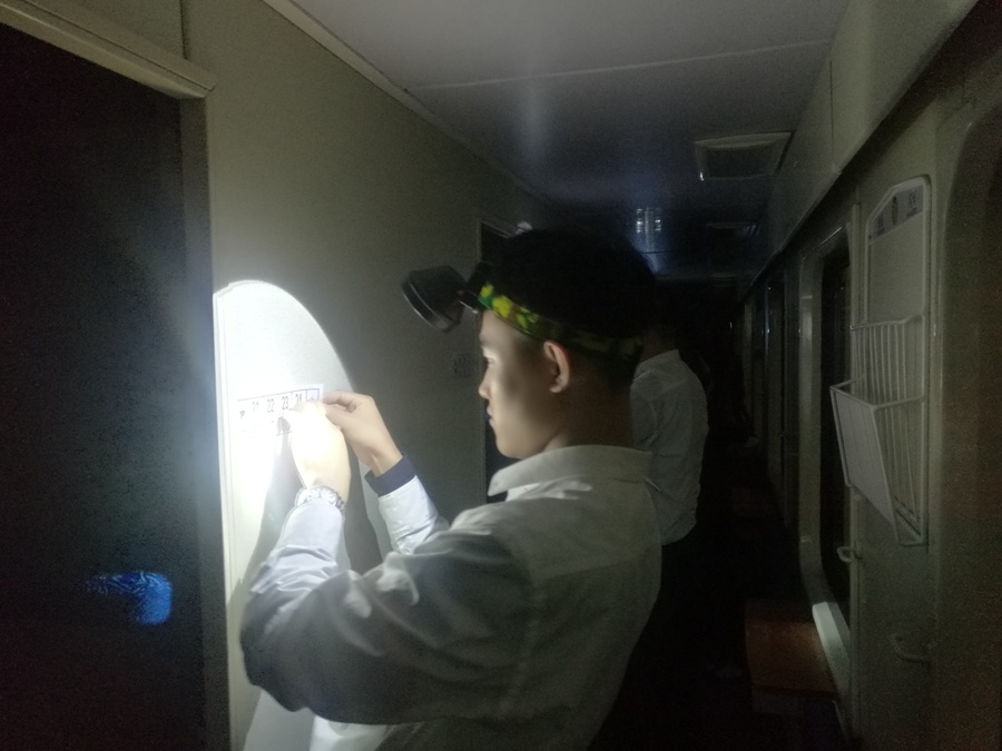 列車長打開頂燈，帶領休班乘務員對車內揭示揭挂進行認真粘貼。謝風春攝