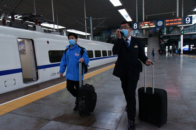 福州站客運車間主任朱劍峰推著箱包，一路護送支援武漢戰疫的陳建華進站乘車。江曲攝