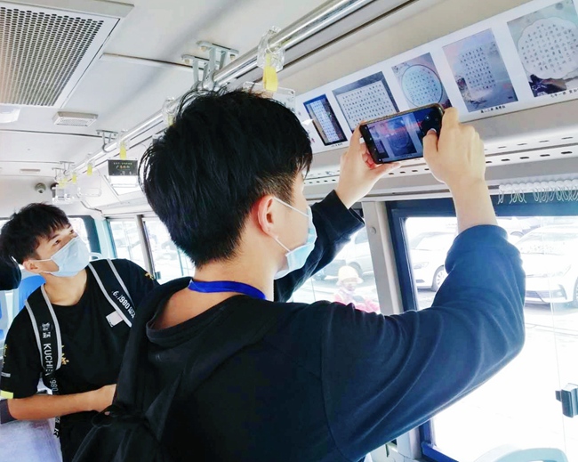 乘客拿出手機拍攝在車廂內的書畫作品。孫慧鴻攝