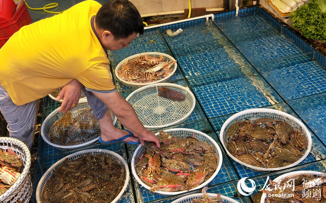 厦门第八市场的海鲜摊主将刚到货的螃蟹按品相分类，价格从十几元到几十元不等。人民网 陈博摄