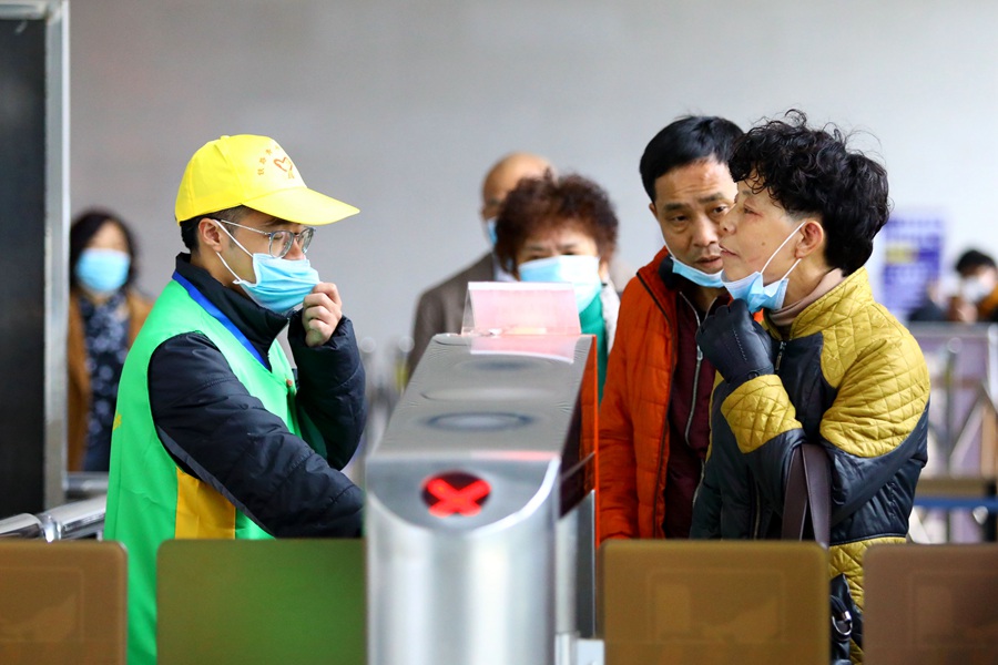 青年志願者引導旅客摘下口罩，進行人臉識別驗証。