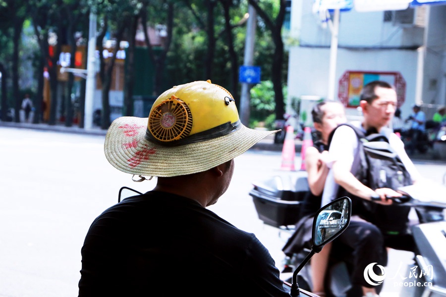 福州街头，有市民头戴内置小风扇的帽子降温。人民网 刘卿摄