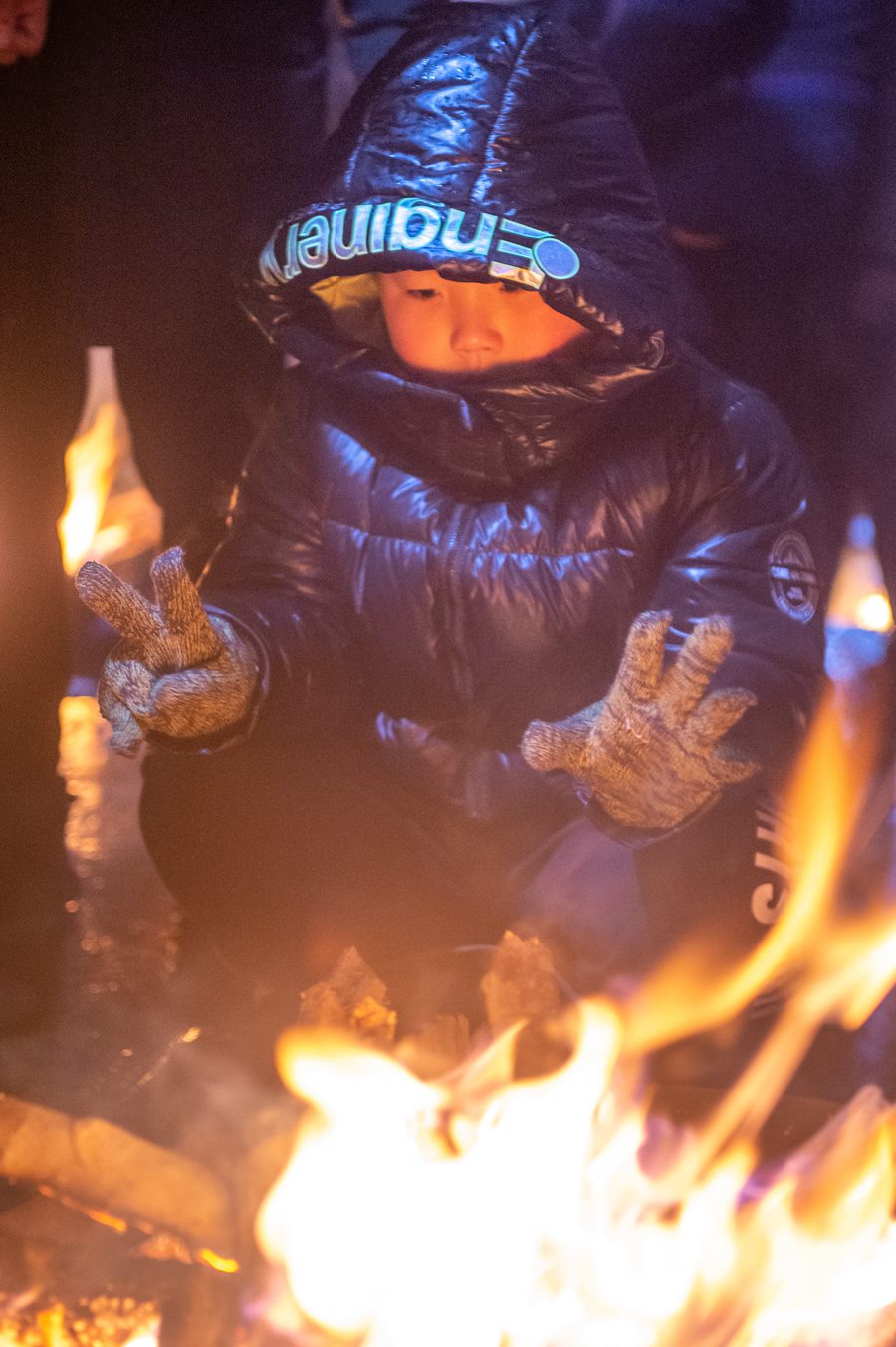 全副“捂”装的孩子在烤火取暖。蔡昊摄