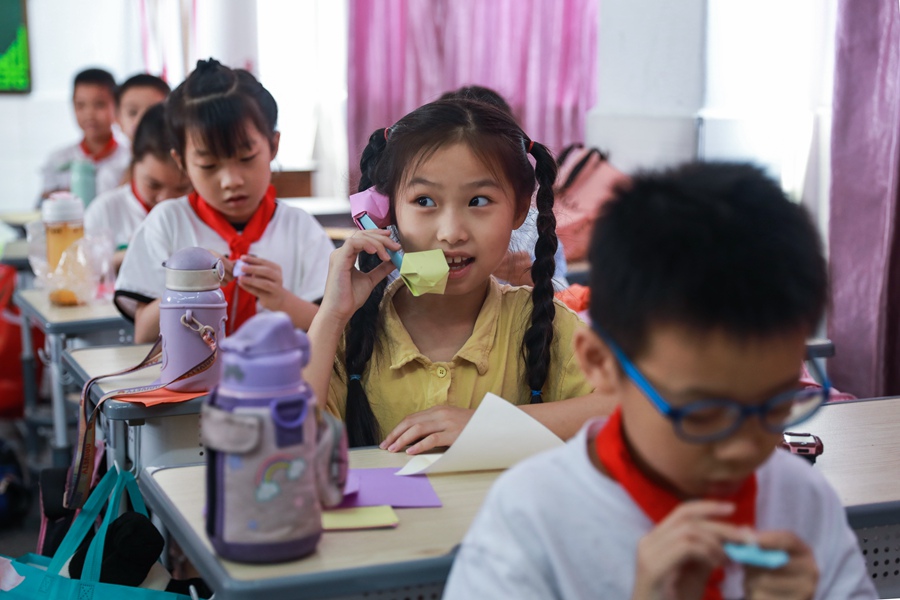 一名学生高兴地用自制折纸电话“通话”。郑文典摄