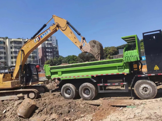 工人正在向电动渣土车内搬运废土。厦门市建设局供图