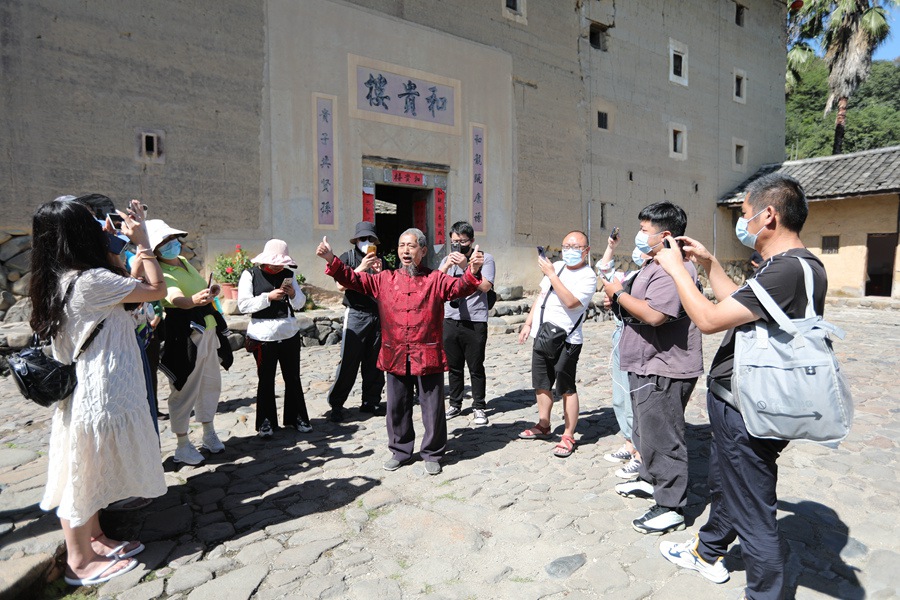 在福建土楼（南靖）景区的和贵楼，楼长简良发向当地群众和游客宣讲党的二十大精神。南靖县融媒体中心供图