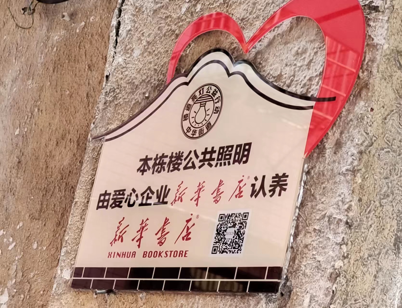中山社区一栋楼门前挂着一块公共照明由爱心企业认养牌子。