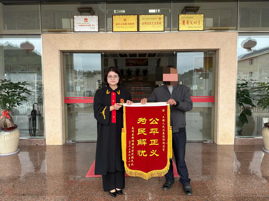 張某將錦旗送到了土樓法庭承辦法官手中。南靖縣融媒體中心供圖