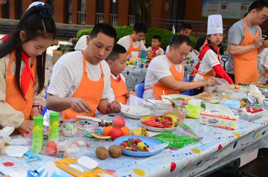 仓四小学生的爸爸和孩子正以“二十大”“春日暖阳”为主题，进行创意水果拼盘，并及时将水果残渣等垃圾进行分类，增强了孩子的动手能力和环保意识。叶诚摄
