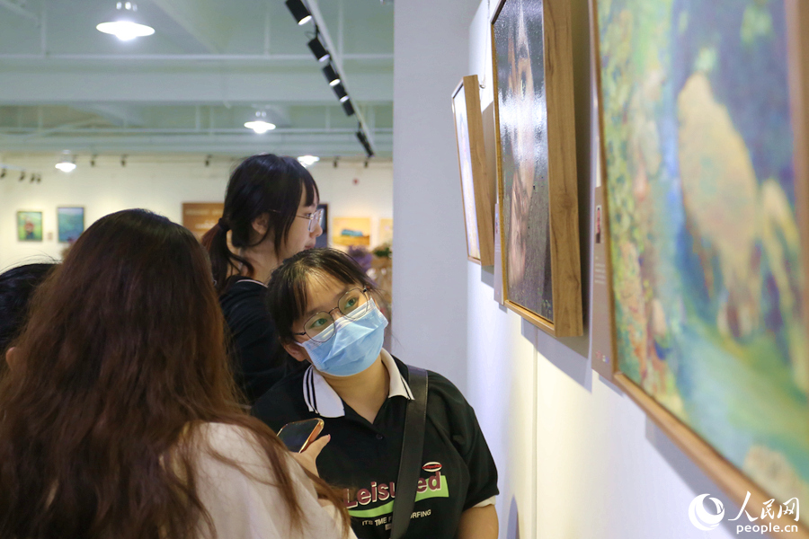 油画爱好者们在参展作品前讨论交流。人民网 陈博摄