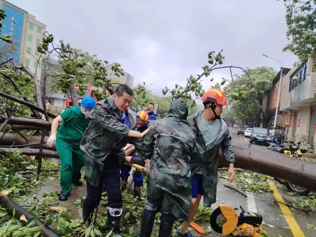 抬起倒下的树木，救助受困群众。福建省公安厅供图