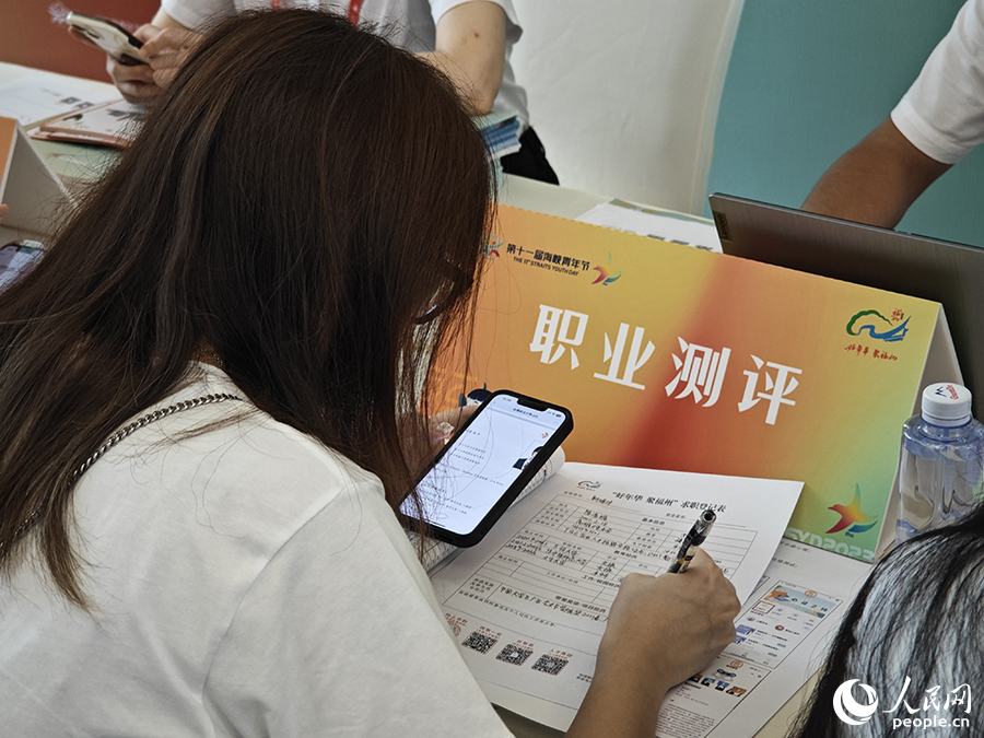 8月10日，“好年华·聚福州”2023年闽台青年人才研学营招聘会现场，一位台湾青年正填写求职材料。人民网 黄东仪摄