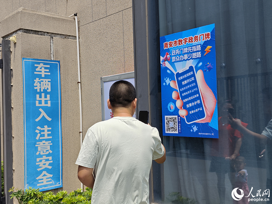 南安市某小区外，市民正在扫描数字政务门牌海报上的二维码。人民网 黄东仪摄