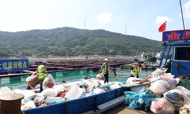 环卫工人们将回收点垃圾整理上船。