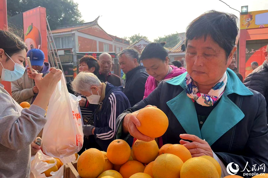 市民、游客在展销摊前选购脐橙。人民网记者 林盈摄