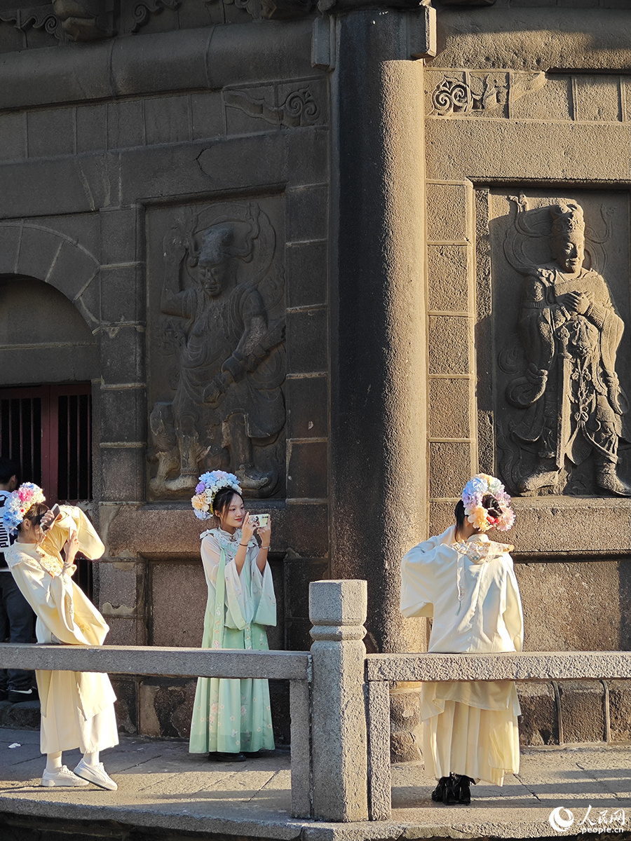 2024年1月18日，三位游客頭戴“簪花”，身著漢服在泉州開元寺鎮國塔下拍照。人民網 黃東儀攝