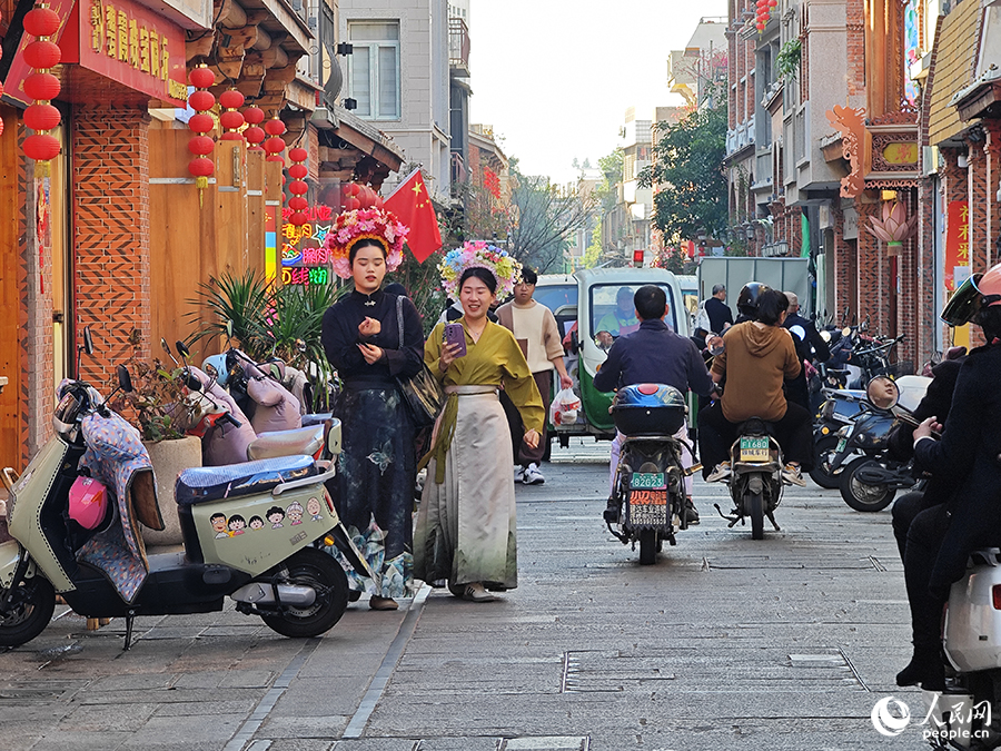 两名头戴“簪花围”的游客行走在泉州古城花巷中。人民网 黄东仪摄