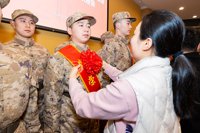 輔導員為入伍新兵佩戴綏帶和大紅花。廈門城市職業學院供圖