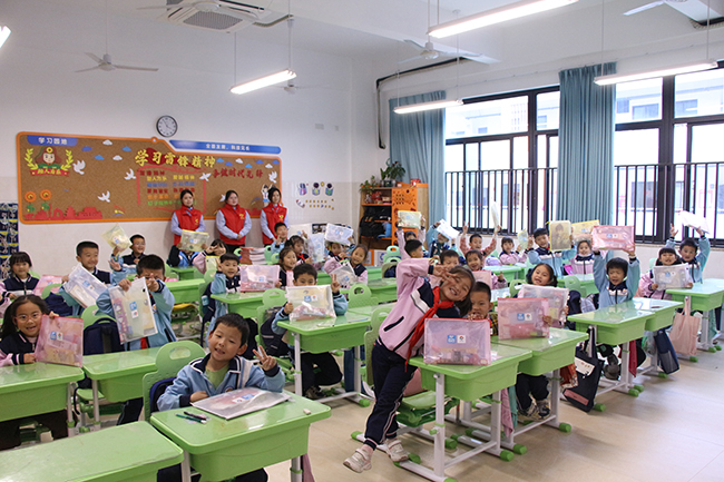 學生們拿著文具禮包露出開心的笑容