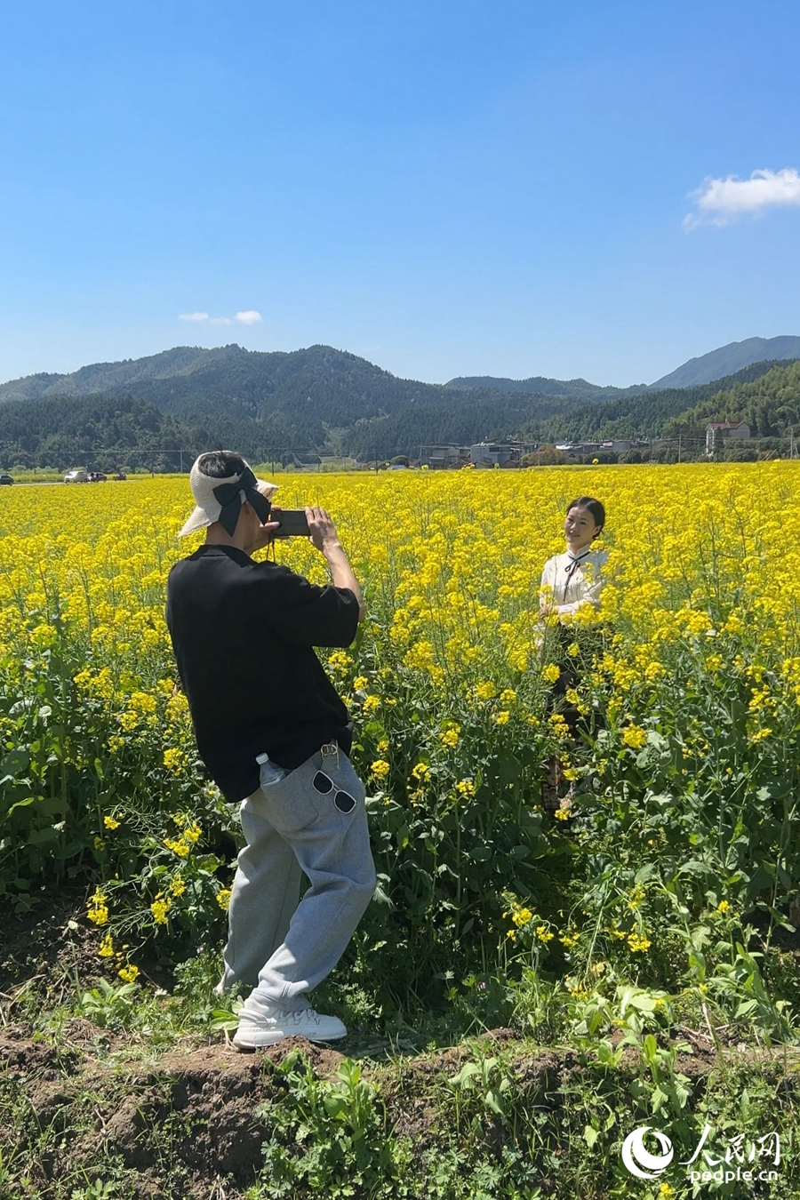 游人们在油菜花海中打卡留念。人民网记者 兰志飞摄