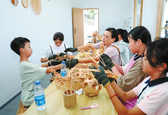 游客在武平縣中山鎮陽民村竹藝制作館中學習竹編。