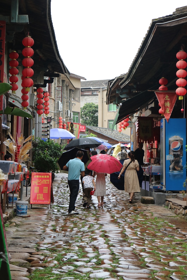 游客在雨中游玩嵩口古镇。林娇摄