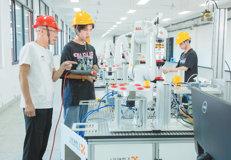 全國先進工作者林福（左）指導學生操作工業機器人