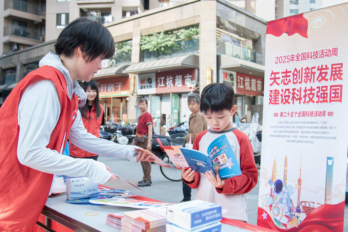 2025年全國科技活動周現場，志願者向小學生遞發水利科普資料。陳美蓉攝