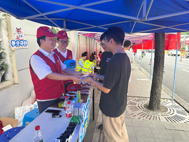 在四川师范大学附属中学的爱心助考点，中建海峡西南公司“蜀光”志愿者们向考生送上应急文具