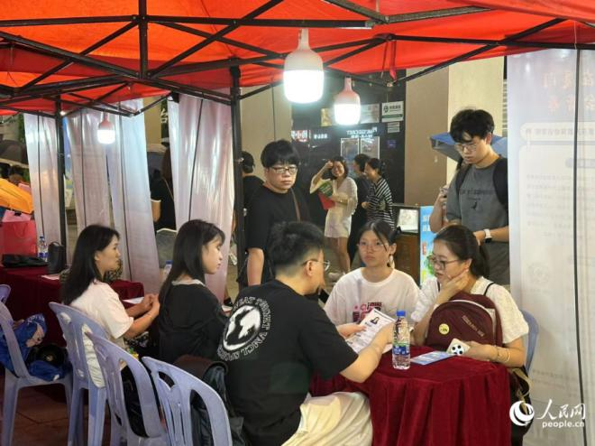 夜市招聘會上,求職大學生正在與用人單位進行交流。人民網記者 張萌攝