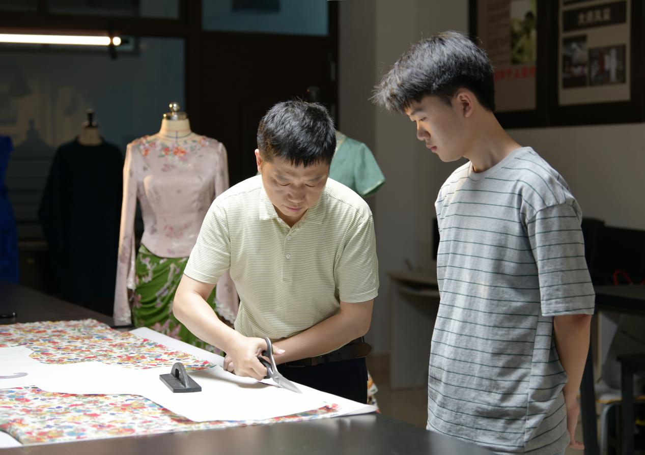 封卫平与学生设计服装版型。