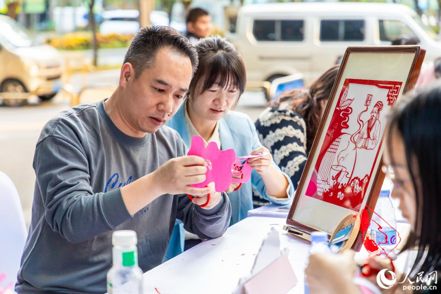市民在户外雅集区体验剪纸。人民网摄