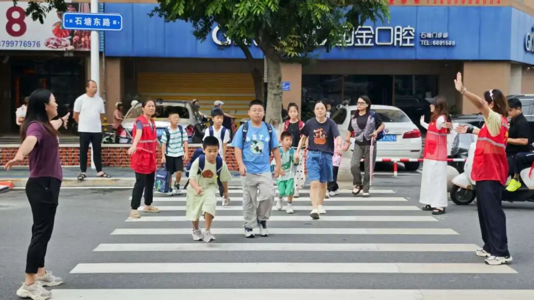身着红马甲的志愿者引导学生通行