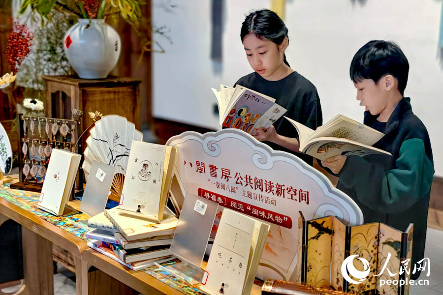 两位来自新加坡的小朋友饶有兴趣地翻看起介绍福州的书籍。人民网记者 叶青卿摄