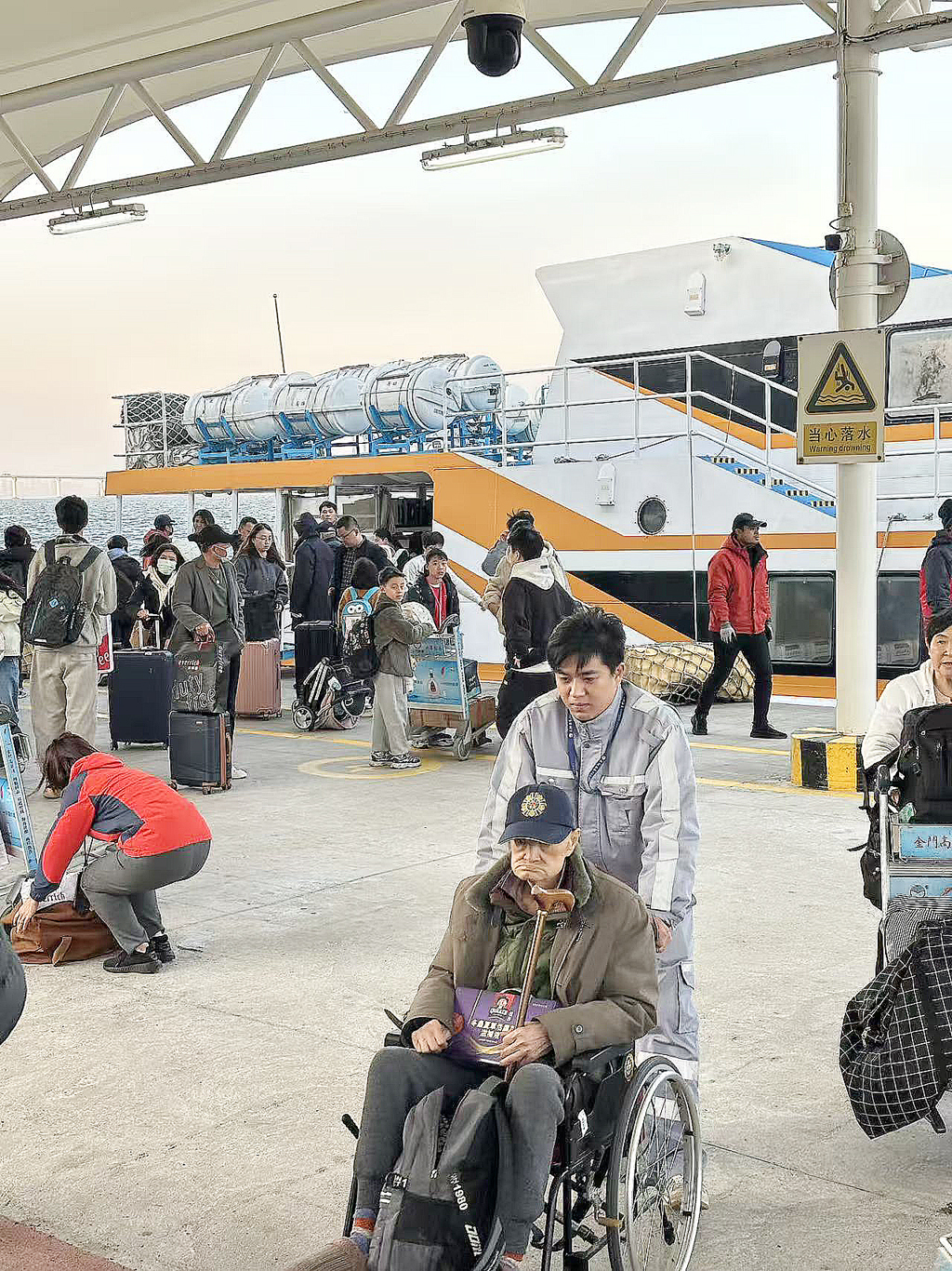 乘坐马可波罗1号客船旅客，船停后码头工作人员用轮车协助行动不便的旅客。吴榕城摄