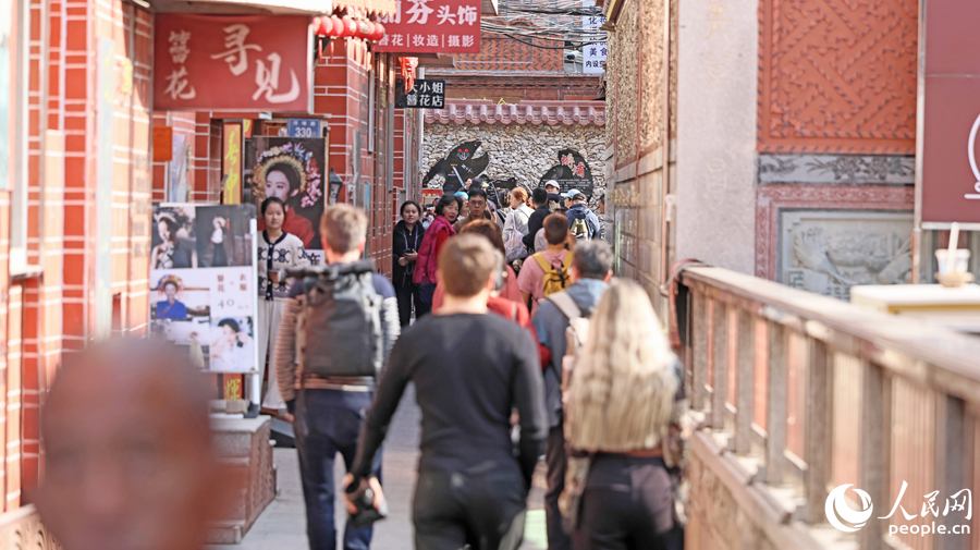 蟳埔古巷游人如织，中外游客体验簪花围，感受闽南风情。人民网记者 李昌乾摄