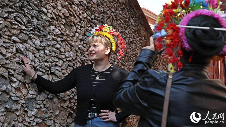 歐洲旅游達人簪花后觸摸蚝殼牆,感受蟳埔漁村的獨特建筑的魅力。人民網記者 李昌乾攝