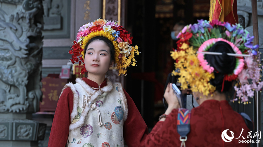 簪花的姑娘在蟳埔廟埕前留影,一襲紅妝配簪花圍,定格閩南習俗的靈動瞬間。人民網記者 李昌乾攝