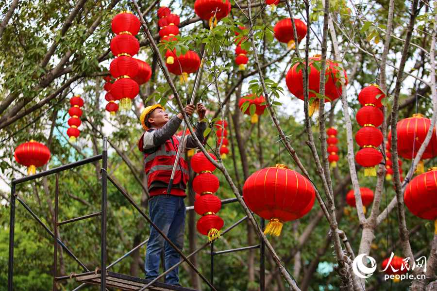 工人爬上脚手架,将一串串喜庆的灯笼安装到位。人民网记者 陈博摄