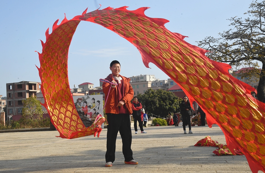 在泉港区后龙镇涂坑古民居百万大厝前广场，游客正在体验舞彩带龙