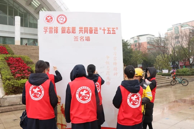 骑手们与现场志愿者一同在签名墙上签名