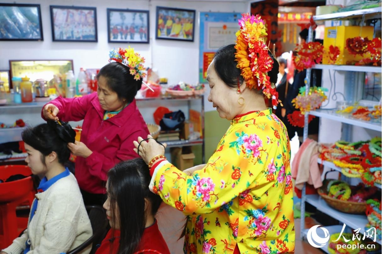 在福建省泉州市蟳埔村，当地村民正在为游客簪花。人民网记者 李唯一摄