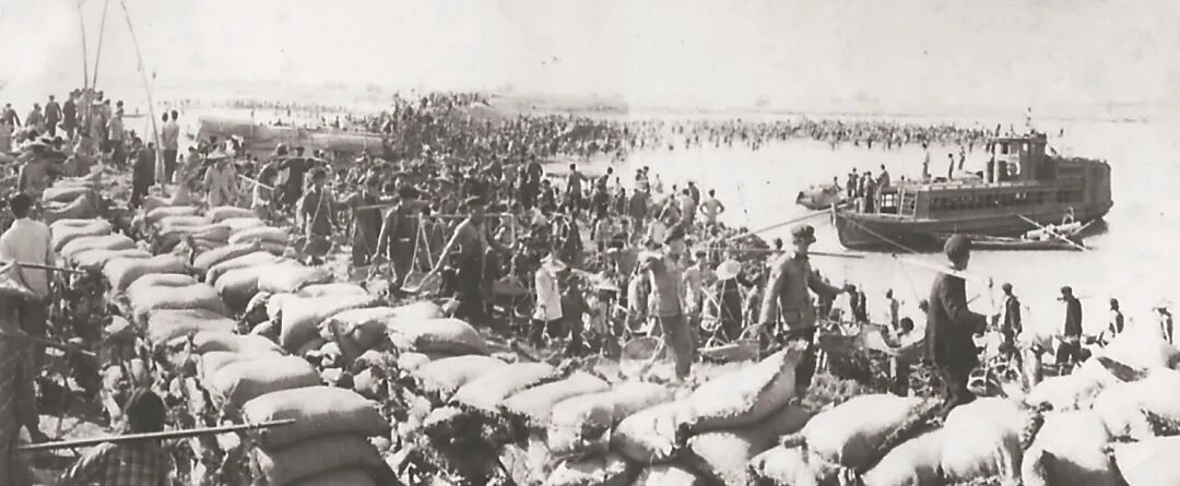 为了在大潮到来之前实现大坝合龙，挑沙的人们与潮水赛跑。（资料图片）