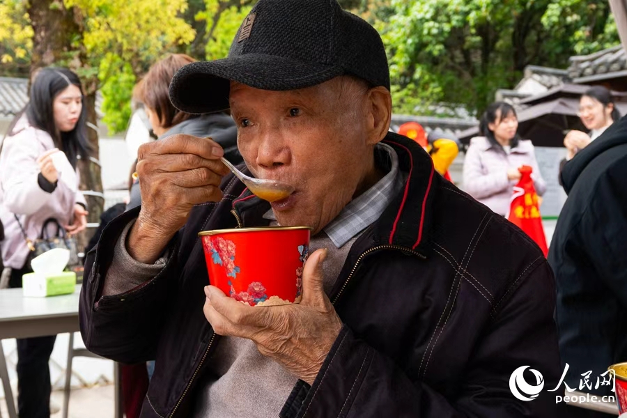 工作人员为现场老人送上热气腾腾的拗九粥,下图为85岁吴老先生在品粥。实习生 李雨泽摄