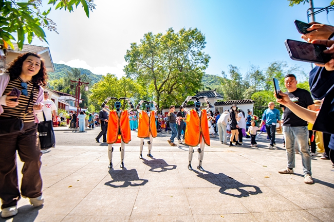 机器人身着民族服饰向路人比爱心。杨柳州摄