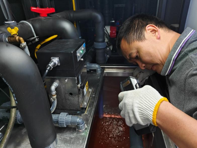 鑫叶公司技术人员佩戴手套精细调试管路阀门，于毫厘之间保障润版液供给稳定。颜荣摄