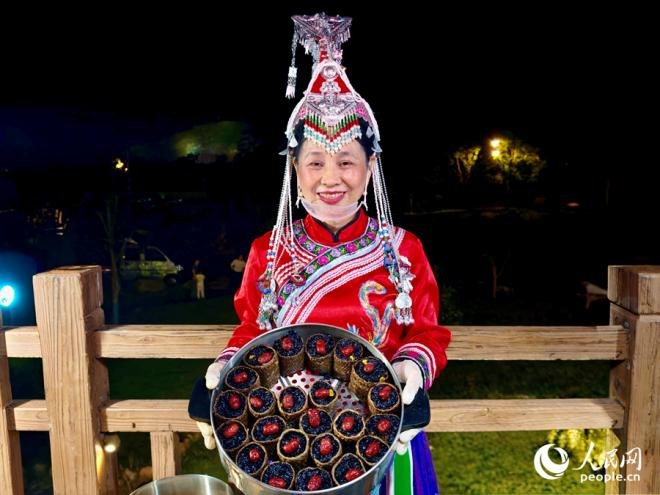 夜市上，摊主向游客展示特色小吃。人民网 杨灏昱摄